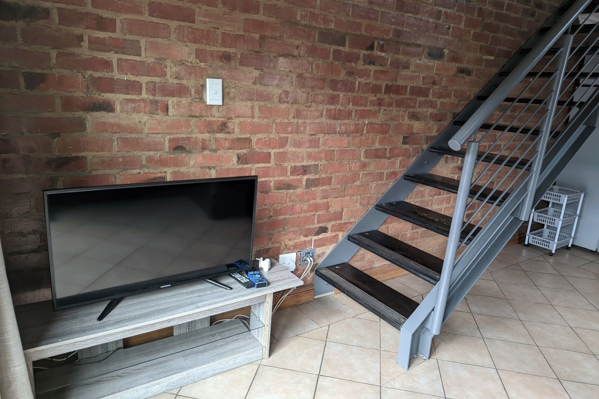 Living area featuring an industrial-style exposed brick wall and a modern metal staircase leading to the upper level.