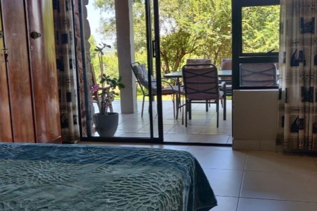 Bedroom featuring tiled flooring, built-in wooden cupboards, and a sliding glass door providing direct access to an outdoor patio area.