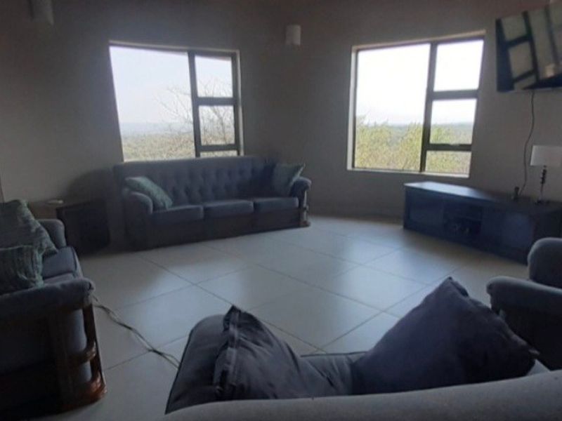 Spacious living room featuring large windows with natural light, tiled flooring, and access to an outdoor area.