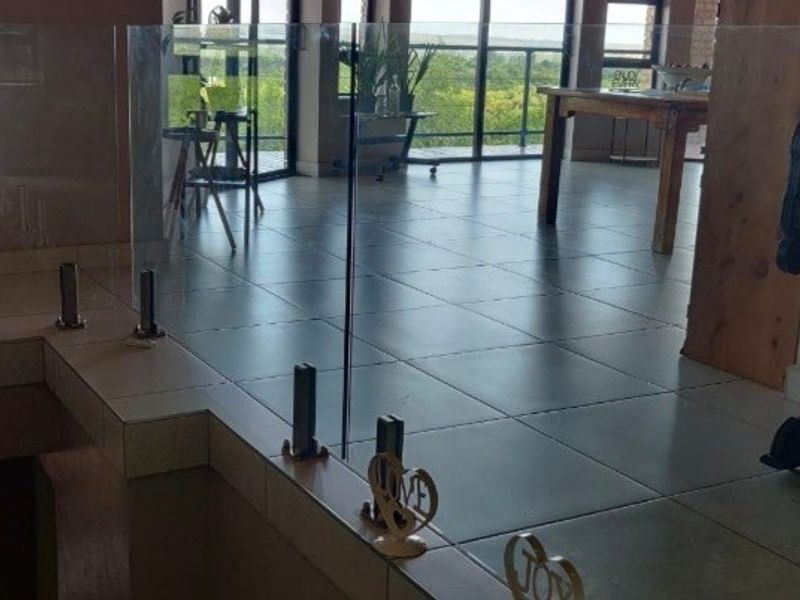 Spacious living area featuring modern glass balustrades, tiled flooring, and large sliding doors that provide ample natural light and scenic views.