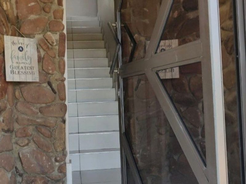 Entrance area featuring a tiled staircase, metal security gate, and rustic stone wall cladding.
