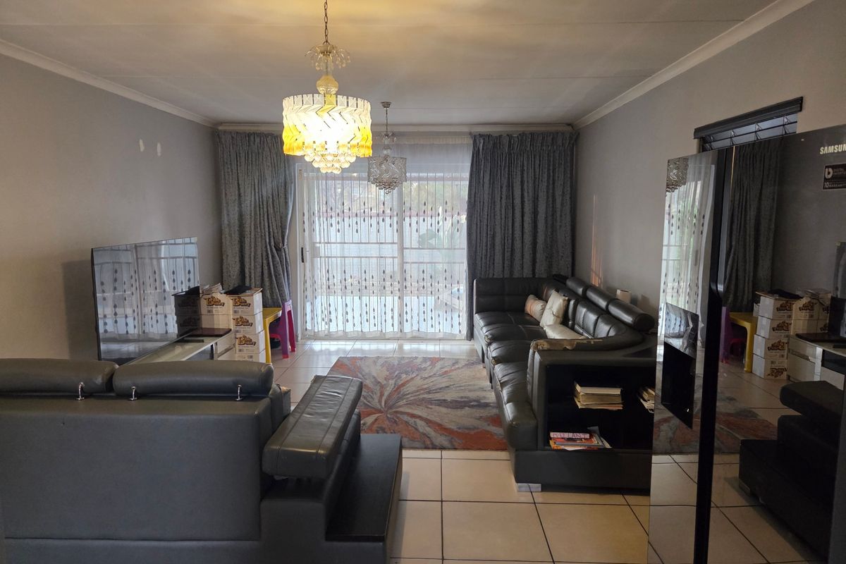 Spacious living room featuring tiled flooring, coved ceilings, and a large sliding glass door providing access to the outdoor area.