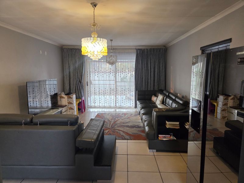 Spacious living room featuring tiled flooring, coved ceilings, and a large sliding glass door providing access to the outdoor area.