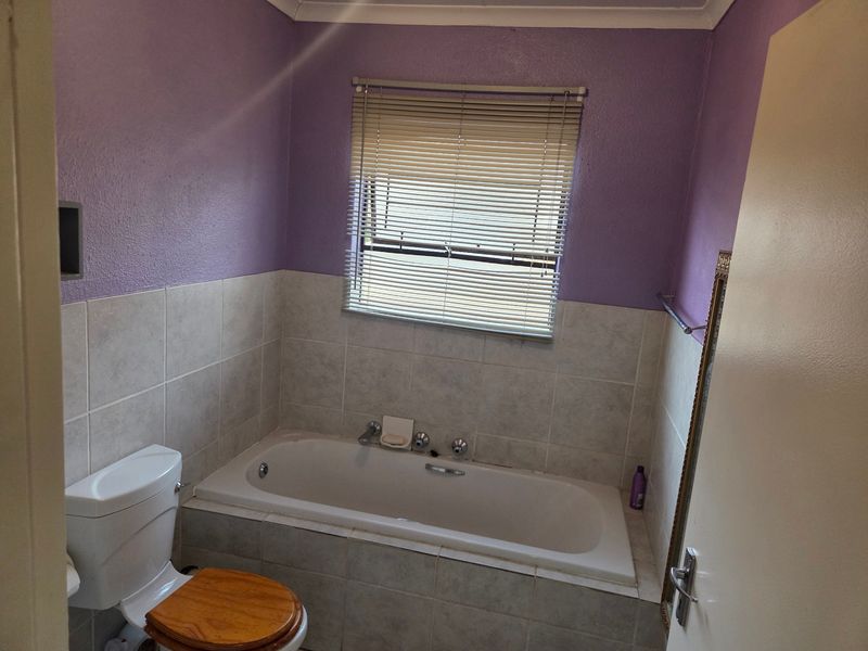 A functional bathroom featuring a built-in bathtub, toilet, and tiled wall finishes, ready for a modern update.