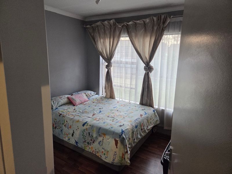 A standard bedroom featuring laminate flooring and neutral wall finishes, offering a functional space with natural light from the window.