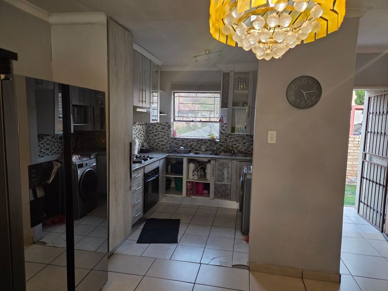 Functional kitchen featuring built-in cabinetry, mosaic tile backsplash, and integrated appliances, with direct access to an exterior area through a security gate.