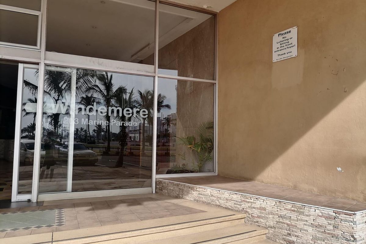 The entrance to Windemere apartments features a large glass facade, tiled steps, and decorative stone cladding on the exterior wall.