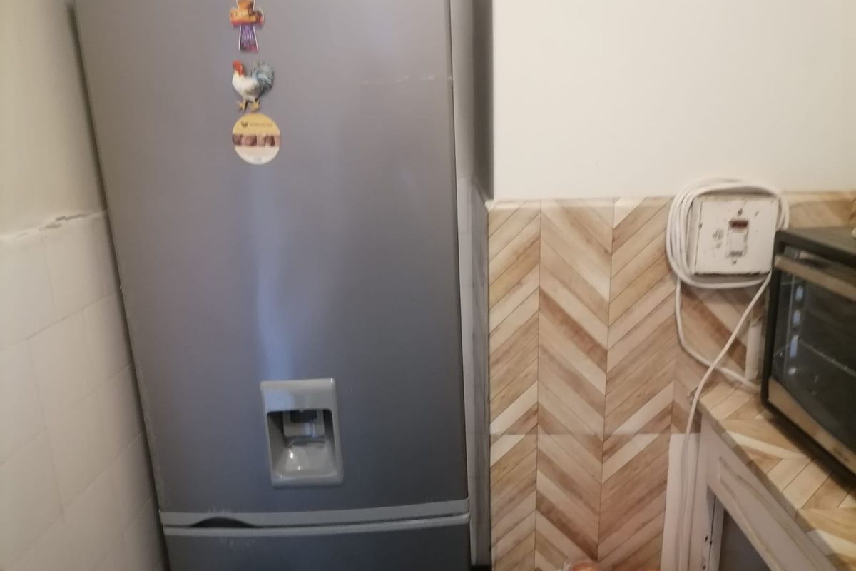 A kitchen corner featuring herringbone patterned wall tiles and visible electrical infrastructure requiring maintenance.