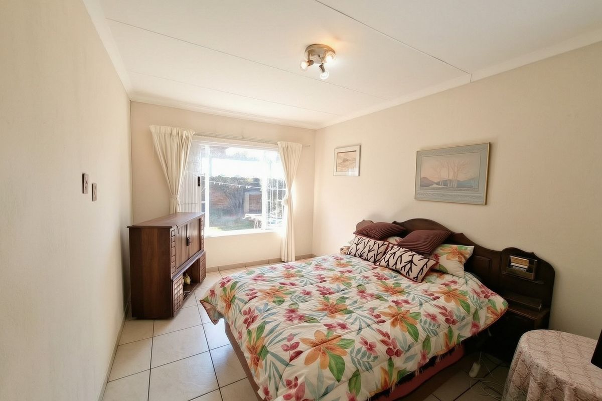 A functional bedroom featuring tiled flooring, a central ceiling light, and a window providing natural light.