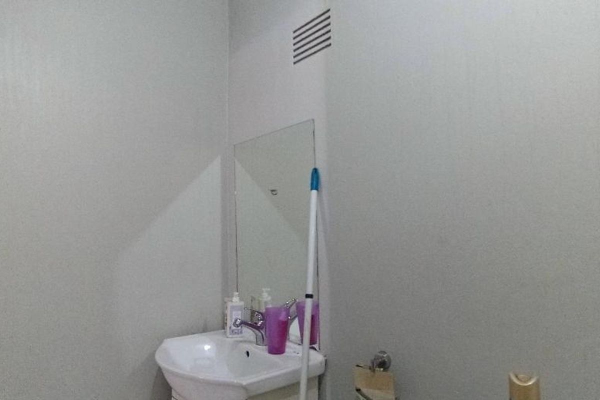 A simple bathroom featuring a wall-mounted basin with a mixer tap and a wall mirror.