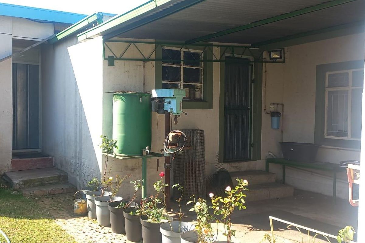 Rear exterior view of the property featuring a covered patio area, water storage tank, and utility sink with access to the main dwelling.