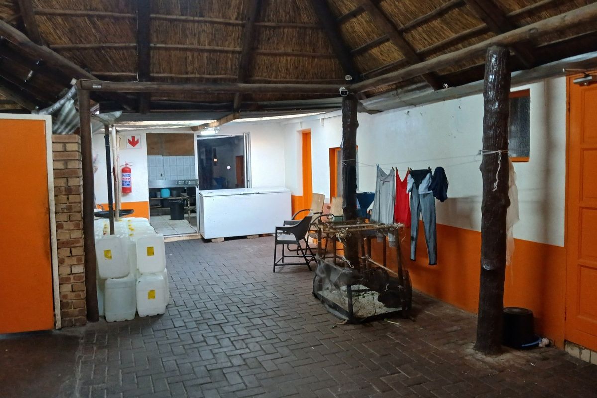 Covered outdoor patio area featuring a traditional thatched roof, brick paving, and exposed timber support posts, providing a functional sheltered space.