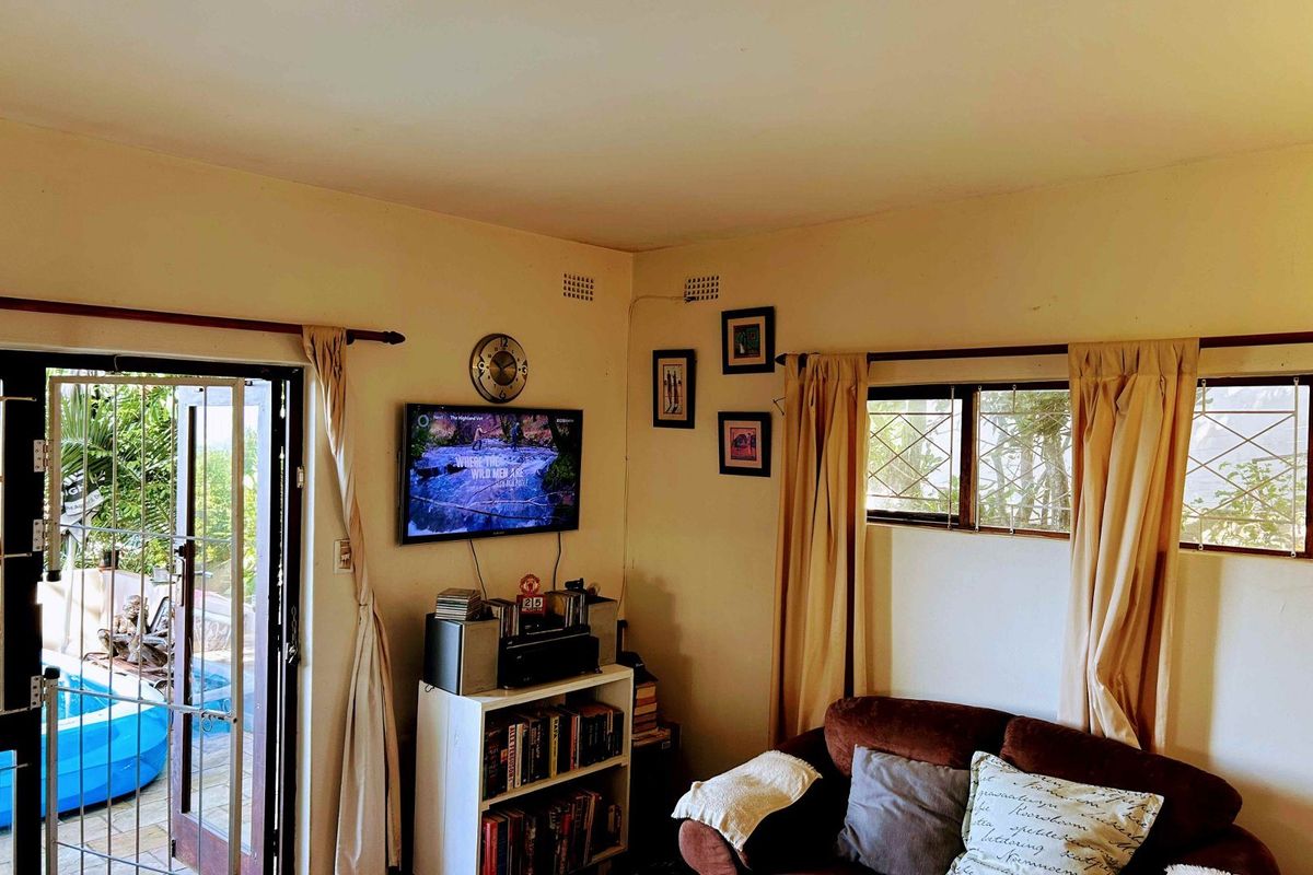 A living room featuring security gates and window bars, with direct access to an outdoor pool area.