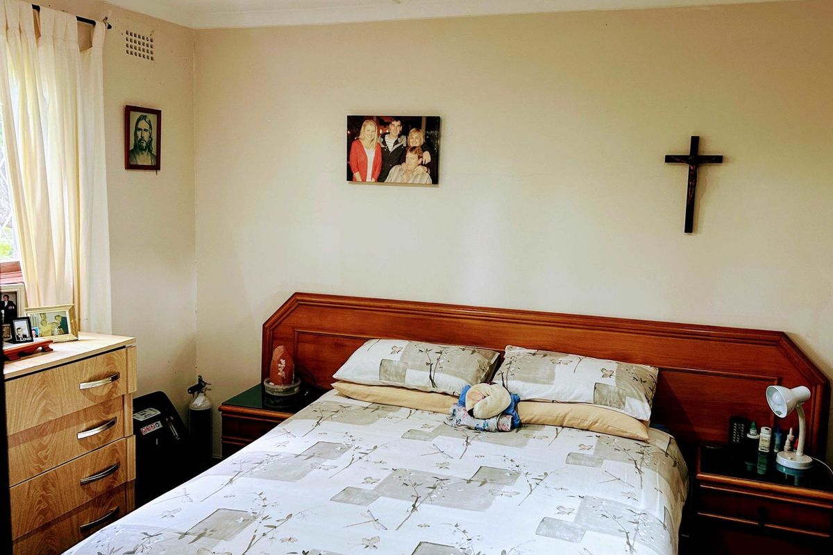 A standard bedroom featuring a built-in wooden headboard and neutral wall finishes.
