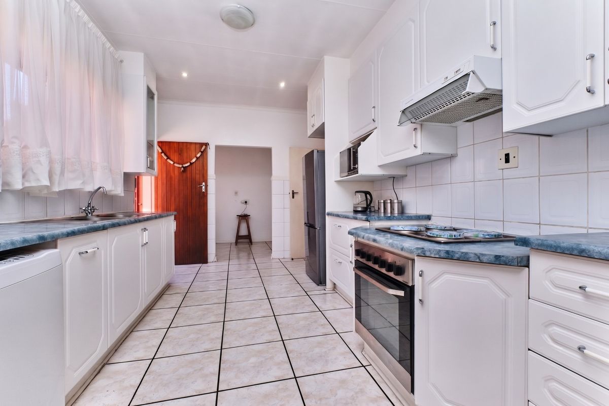 A functional kitchen featuring white cabinetry, laminate countertops, built-in oven with hob, and tiled flooring throughout.