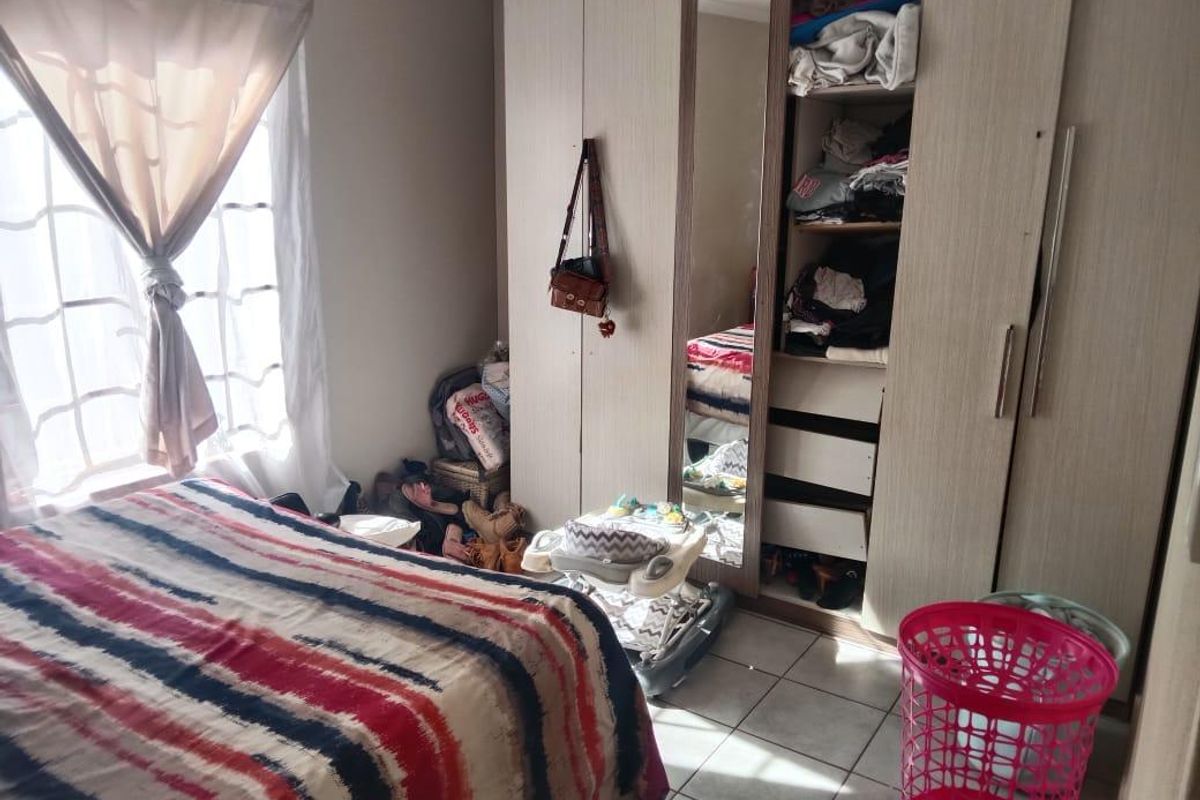 A bedroom featuring tiled flooring and a built-in wardrobe with a mirrored door panel.