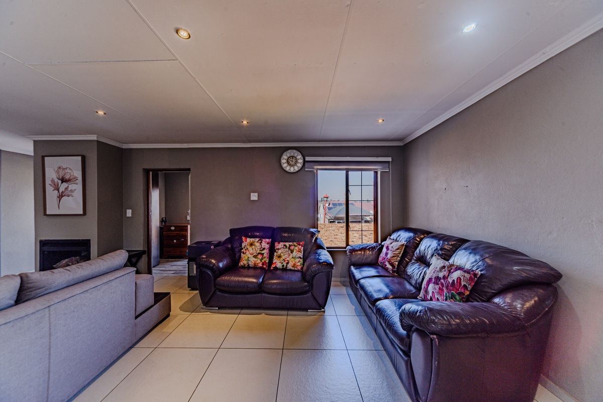 A spacious living room featuring tiled flooring, recessed downlighting, and a built-in fireplace, offering a comfortable and functional layout.