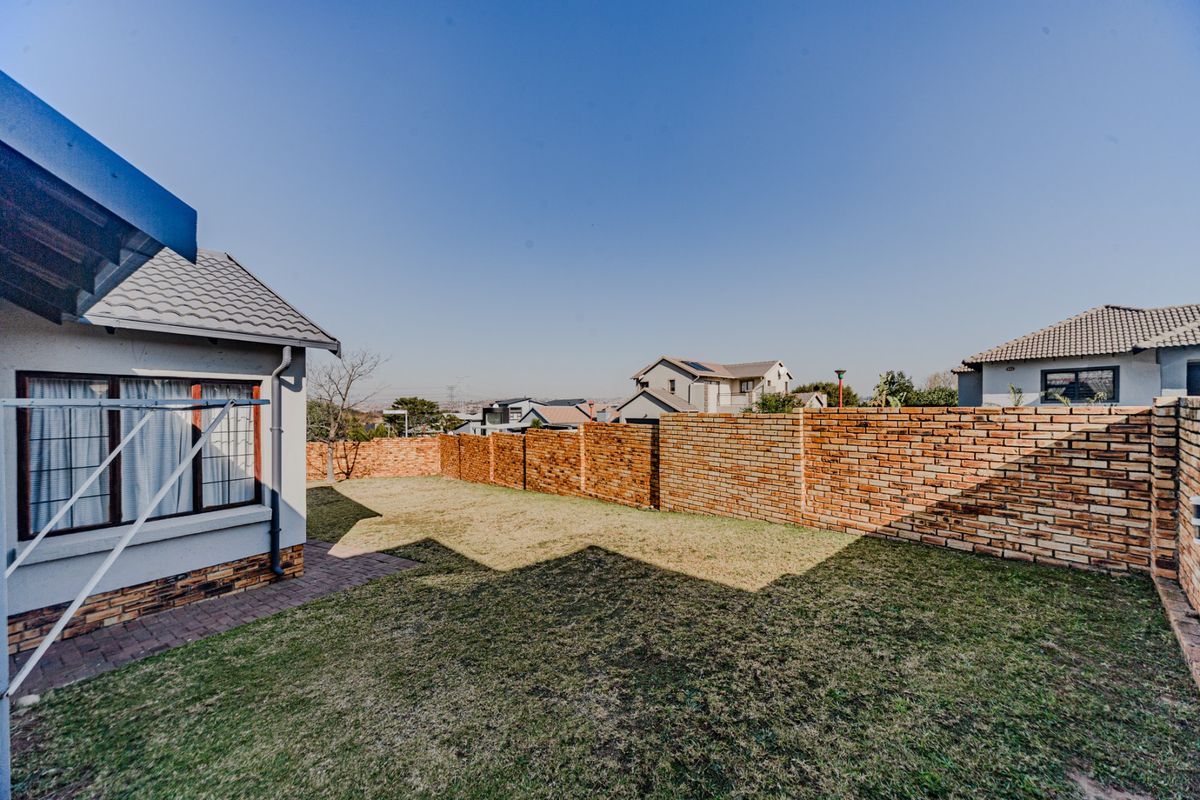 A private rear garden featuring a well-maintained lawn, paved walkway, and a sturdy brick boundary wall, offering a clean and functional outdoor space.