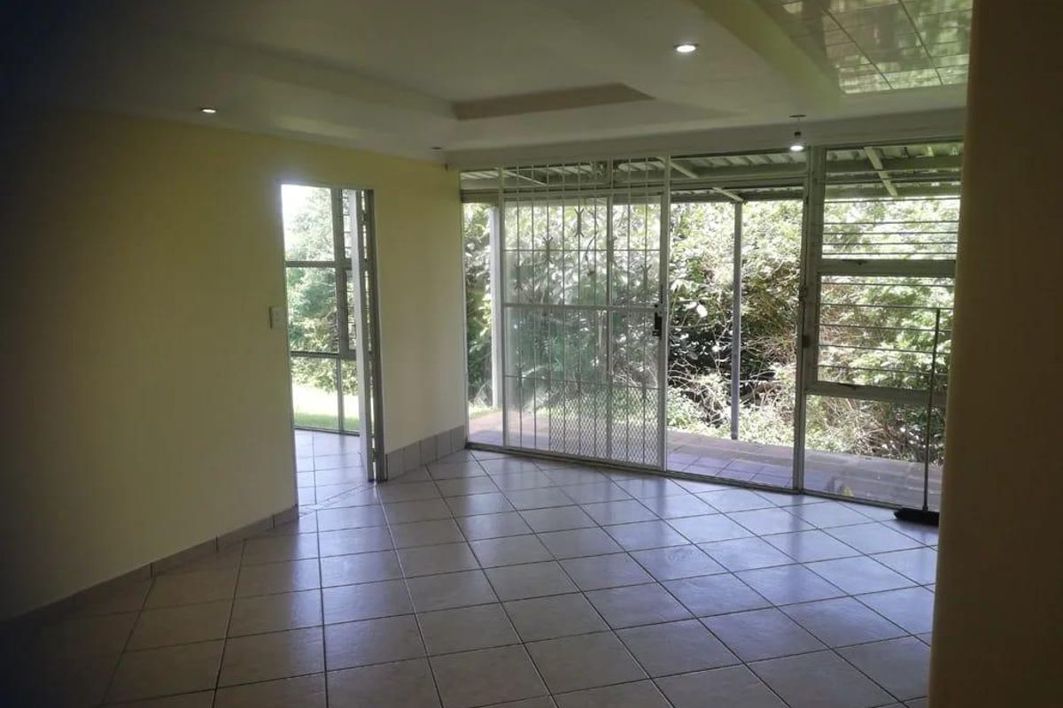 An empty living area featuring tiled flooring, recessed ceiling lights, and large sliding glass doors leading to an outdoor patio space.