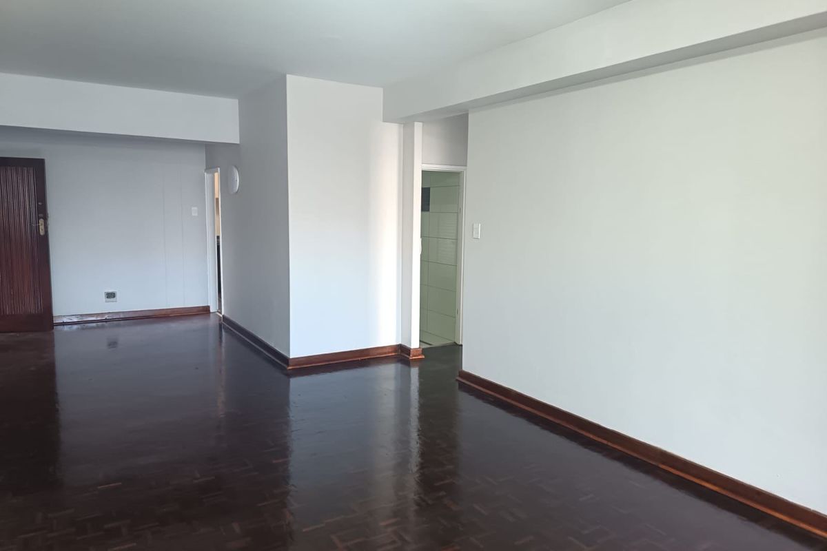 Spacious, empty living area featuring polished parquet flooring, neutral walls, and classic timber finishes, providing a versatile blank canvas for interior design.