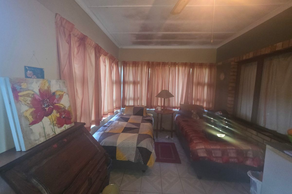 A bedroom featuring tiled flooring, exposed brick accents, and a ceiling fan, currently showing signs of ceiling water damage and wear.