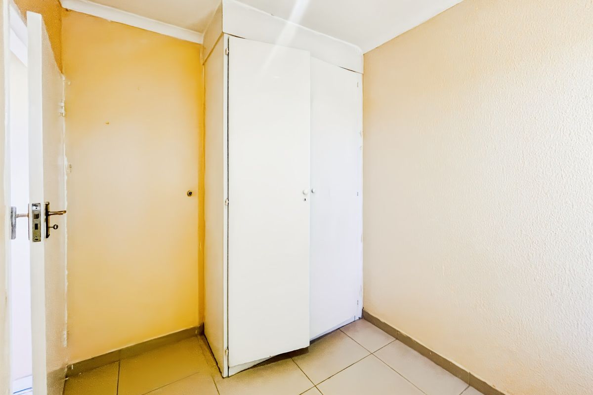 An empty bedroom featuring tiled flooring and a built-in wardrobe, offering a blank canvas for renovation and interior design updates.