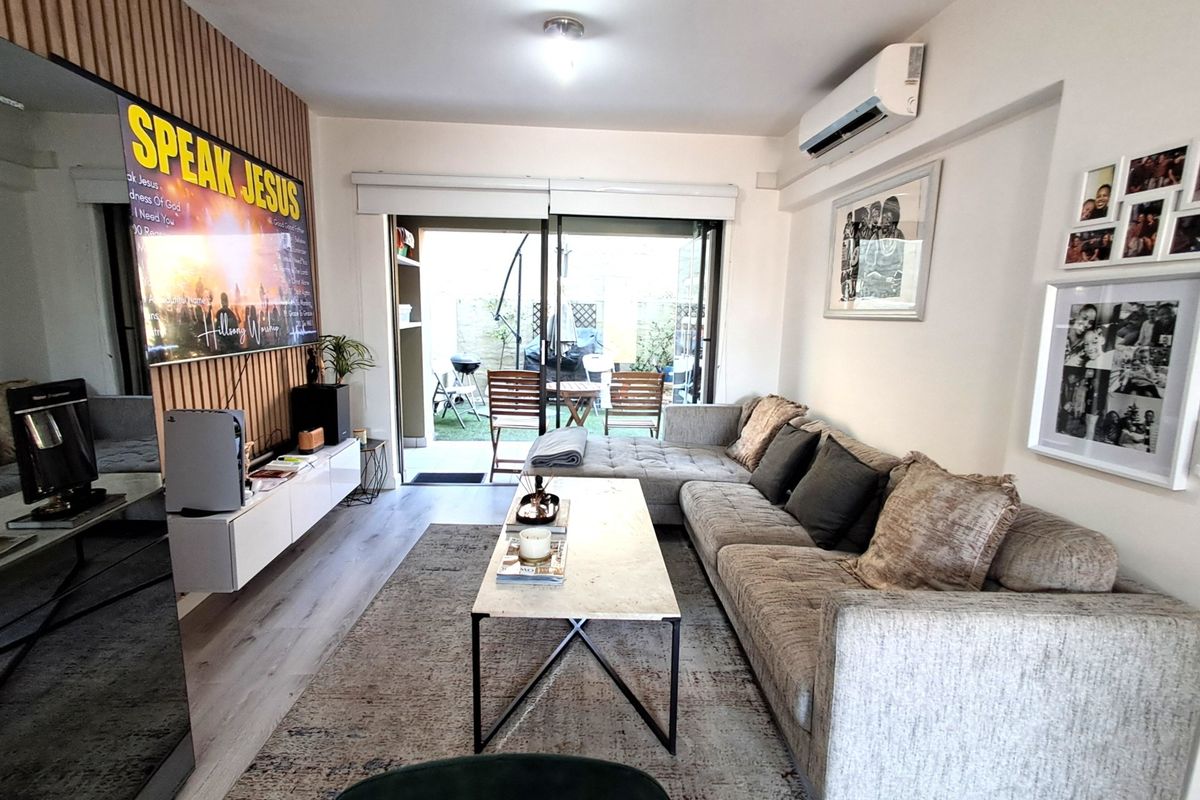 A modern living room featuring a slatted timber accent wall, split-system air conditioning, and direct access to an outdoor patio area through sliding glass doors.