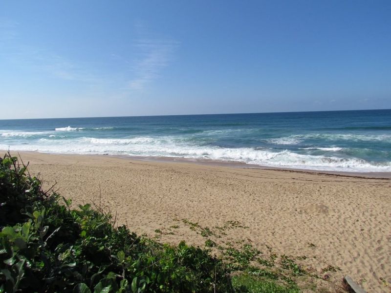 A scenic view of the sandy beach and ocean waves, highlighting the property's coastal location and natural surroundings.