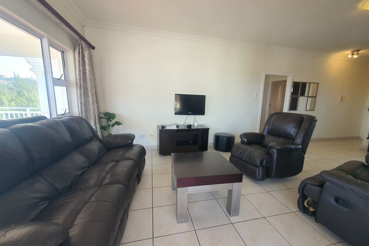 A spacious living room featuring neutral tiled flooring and a large sliding glass door providing natural light and access to the exterior.