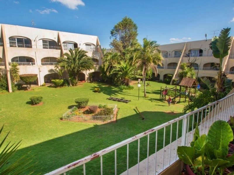 View of a communal garden area surrounded by apartment building blocks with balconies.