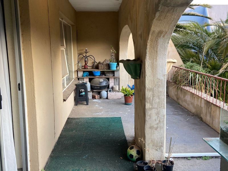 A covered balcony featuring arched masonry columns and a metal railing, offering an outdoor space with potential for refurbishment.