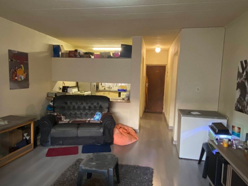 Open plan living area featuring a kitchen pass-through window and direct access to an internal hallway.