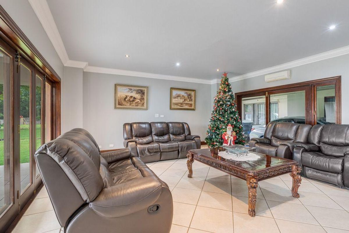 Spacious living room featuring tiled flooring, recessed downlighting, and large timber-framed sliding doors providing access to the outdoor area.