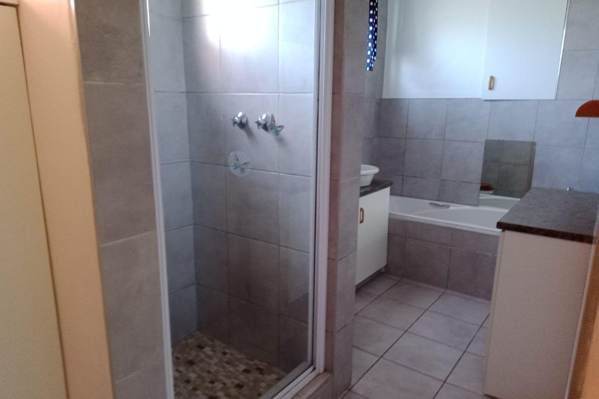 A functional bathroom featuring a separate shower enclosure, a bathtub, and a vanity cabinet with tiled finishes throughout.