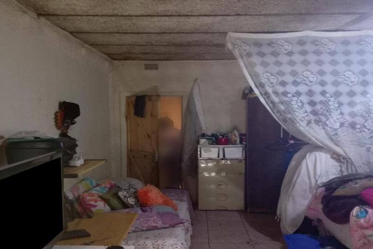 A bedroom featuring tiled flooring, a ceiling fan, and a timber door, currently requiring significant maintenance and cosmetic updates to improve its condition.