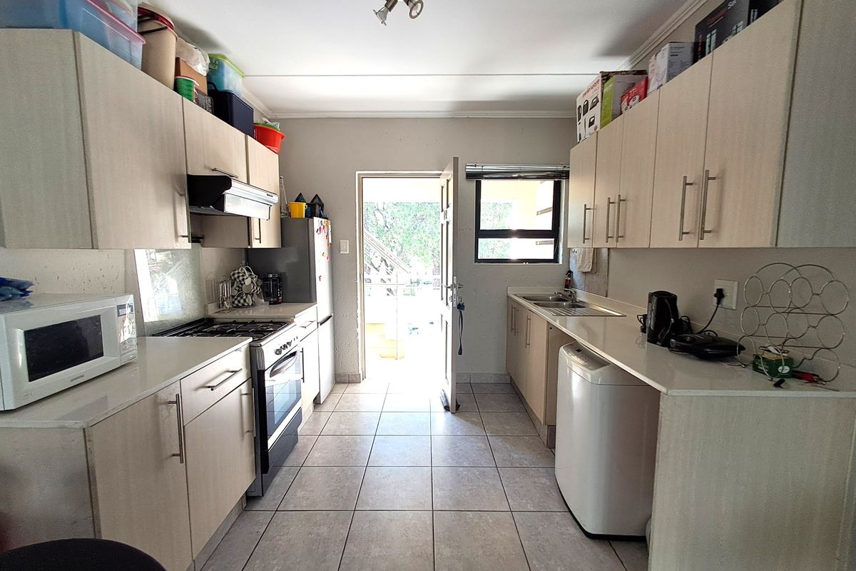 Functional galley-style kitchen featuring light-toned cabinetry, gas stove, extractor fan, and tiled flooring with direct access to an outdoor area.