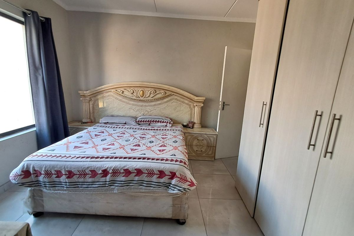 A bedroom featuring tiled flooring and built-in cupboards, offering a functional space with neutral wall finishes.