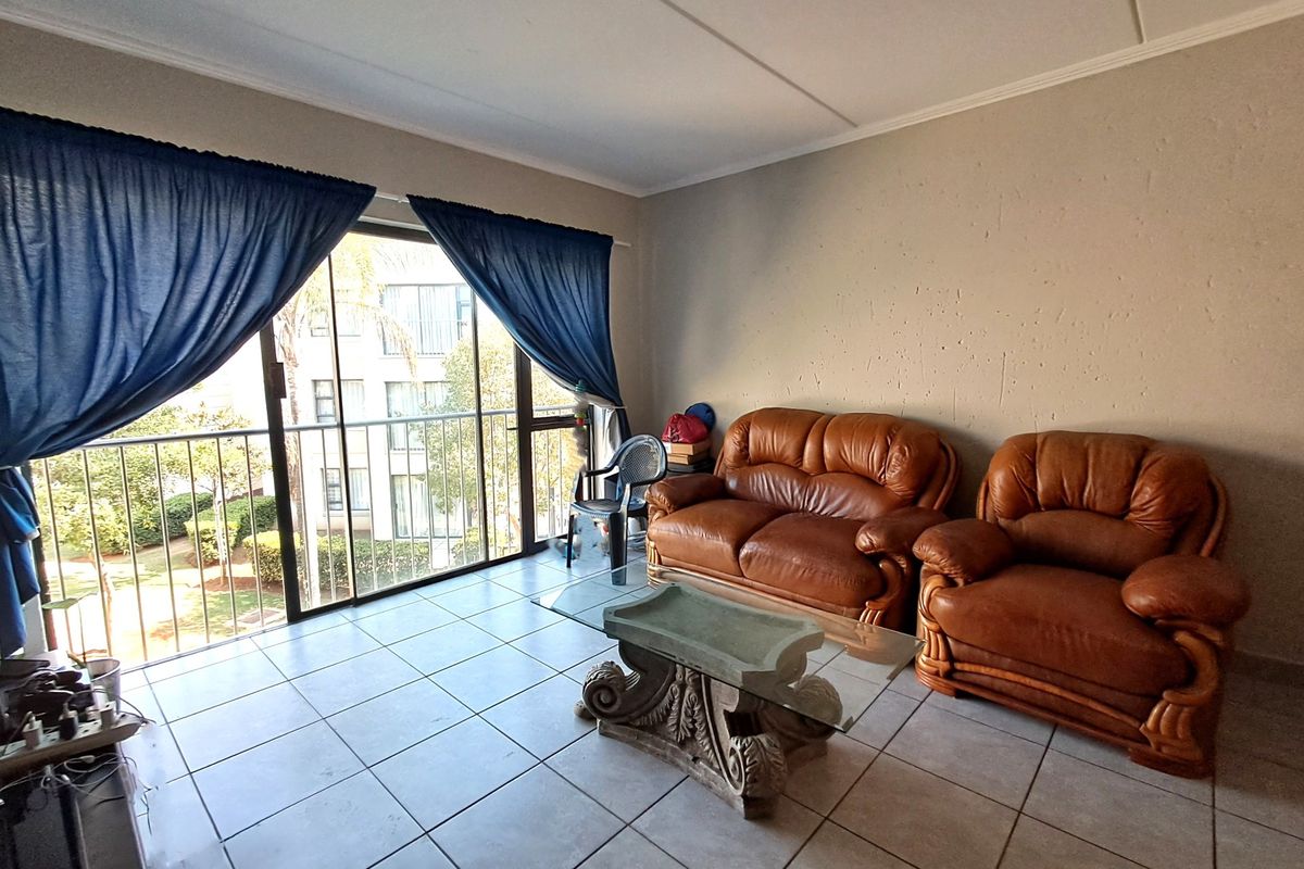 A living room featuring tiled flooring and a large sliding glass door providing access to a balcony.