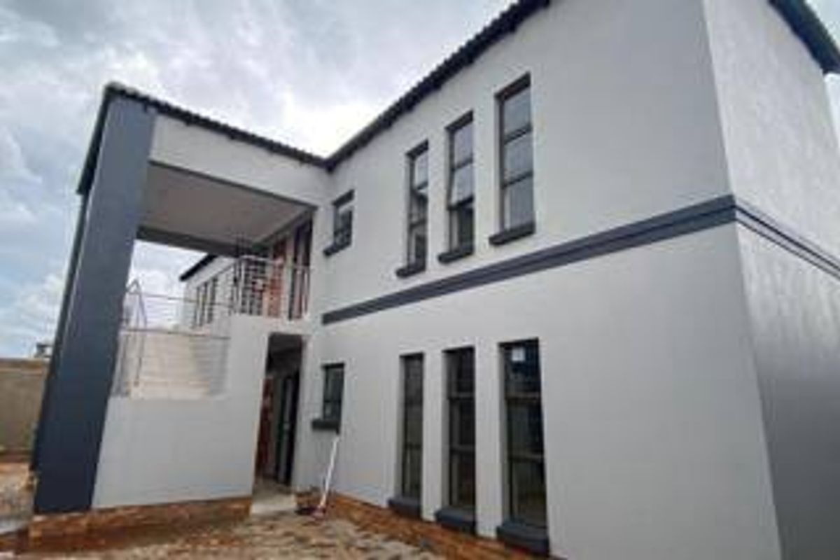 A modern two-story apartment exterior featuring a balcony, external staircase, and contemporary grey facade with large casement windows.