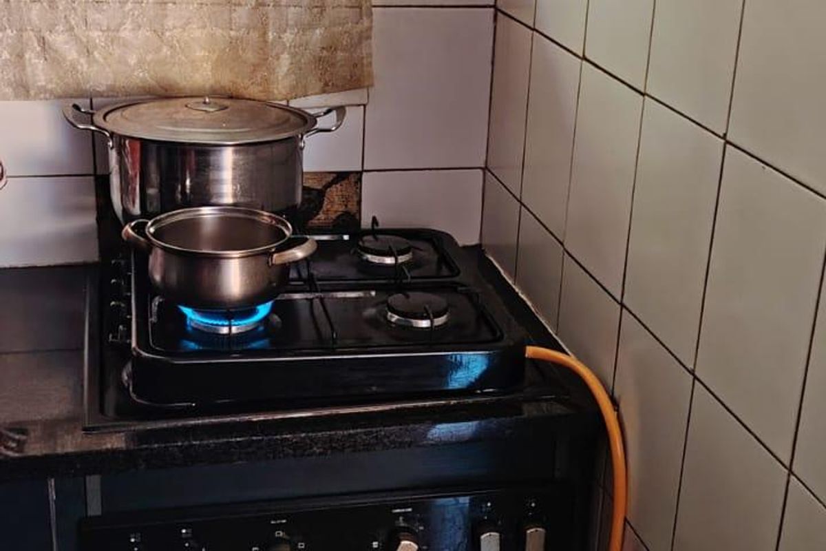 A compact kitchen area featuring a built-in oven, gas hob, and tiled splashback, requiring updates to finishes and gas installation safety.