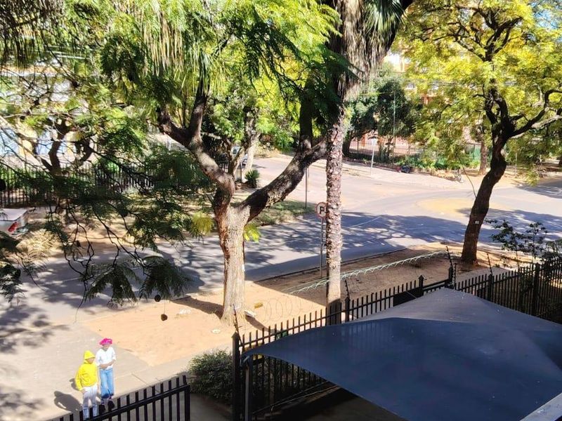 Elevated view overlooking the street, surrounding trees, and neighborhood infrastructure from the apartment balcony.