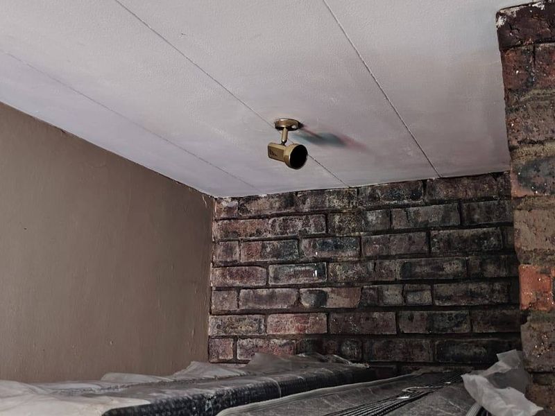 A close-up view of an interior space featuring exposed brickwork and a ceiling-mounted spotlight.