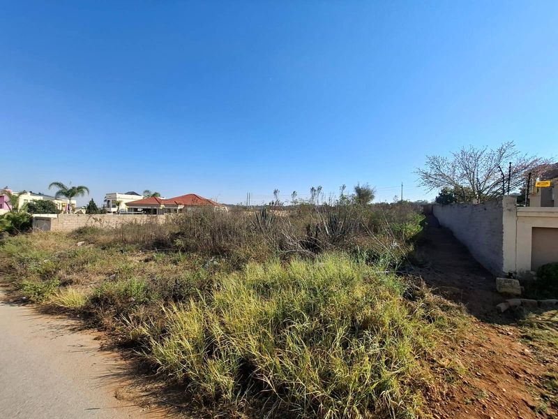 A vacant residential plot featuring overgrown vegetation and existing boundary walls, offering a blank canvas for future development.
