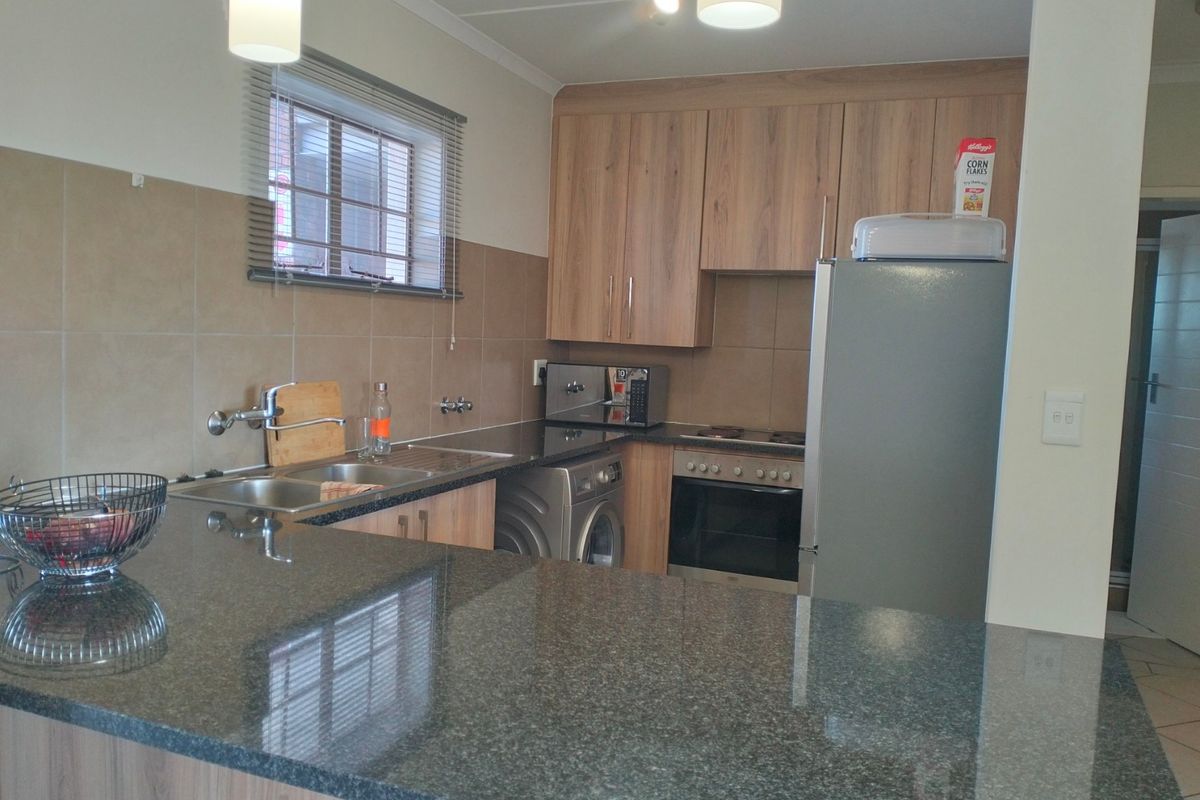 A functional kitchen featuring granite countertops, wood-finish cabinetry, a built-in oven, and a tiled backsplash, offering a practical and well-maintained workspace.