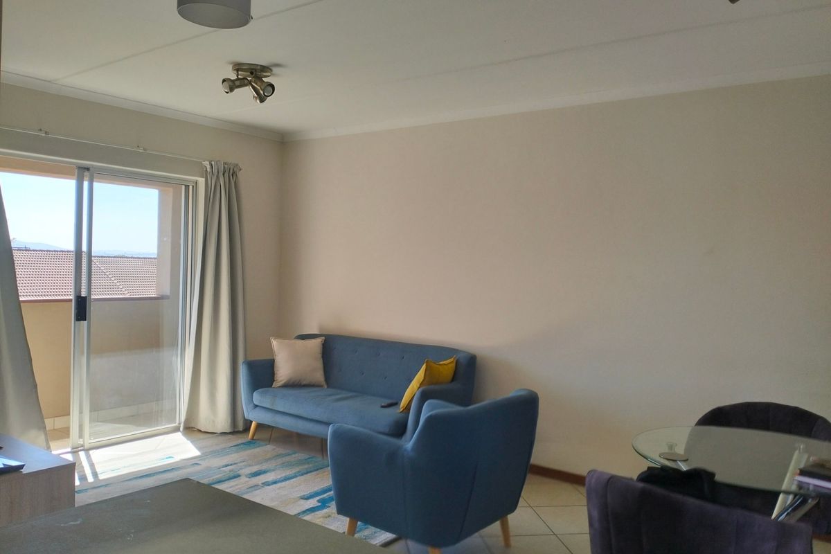 A bright living room featuring tiled flooring and a large sliding glass door providing access to an outdoor balcony area.