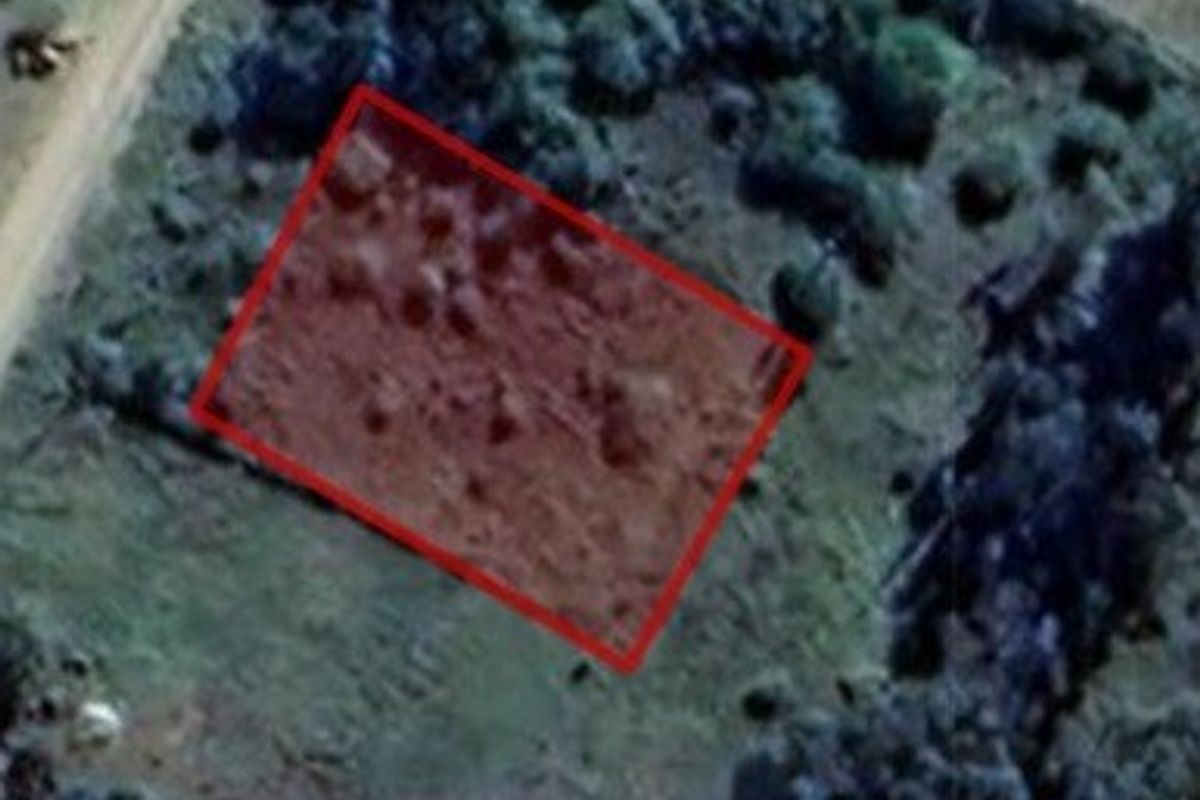 An aerial view of a vacant residential plot outlined in red, showing the surrounding landscape and vegetation.