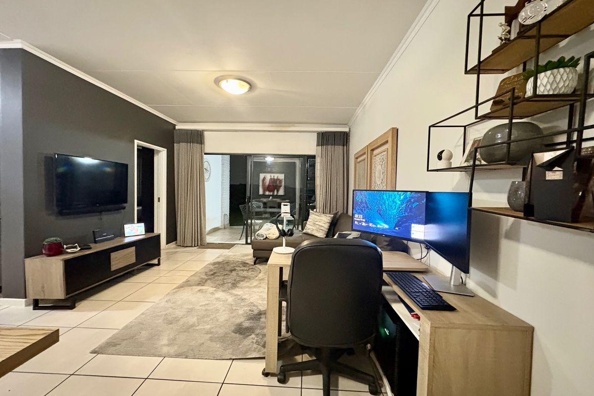 A well-maintained living room featuring tiled flooring, neutral walls, and a sliding glass door providing access to an outdoor patio area.