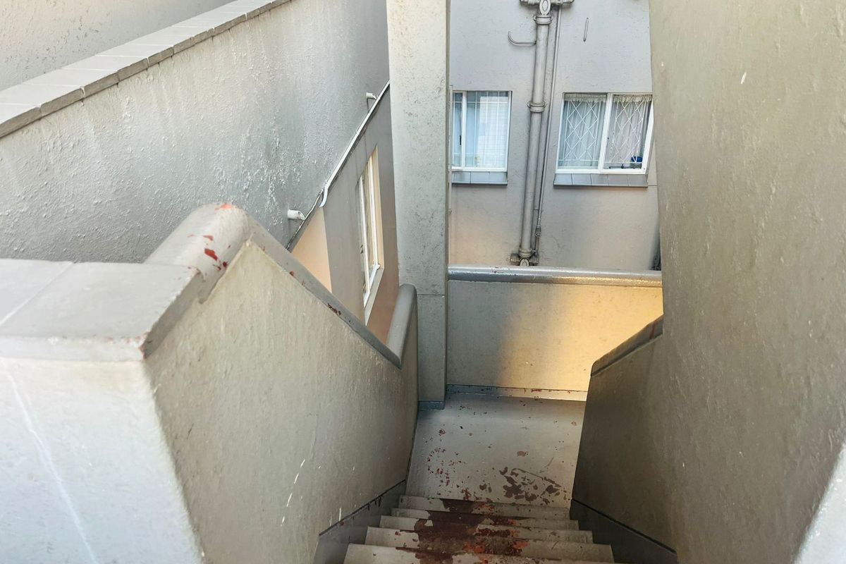 An exterior concrete staircase showing significant wear and peeling paint, providing access between apartment levels.