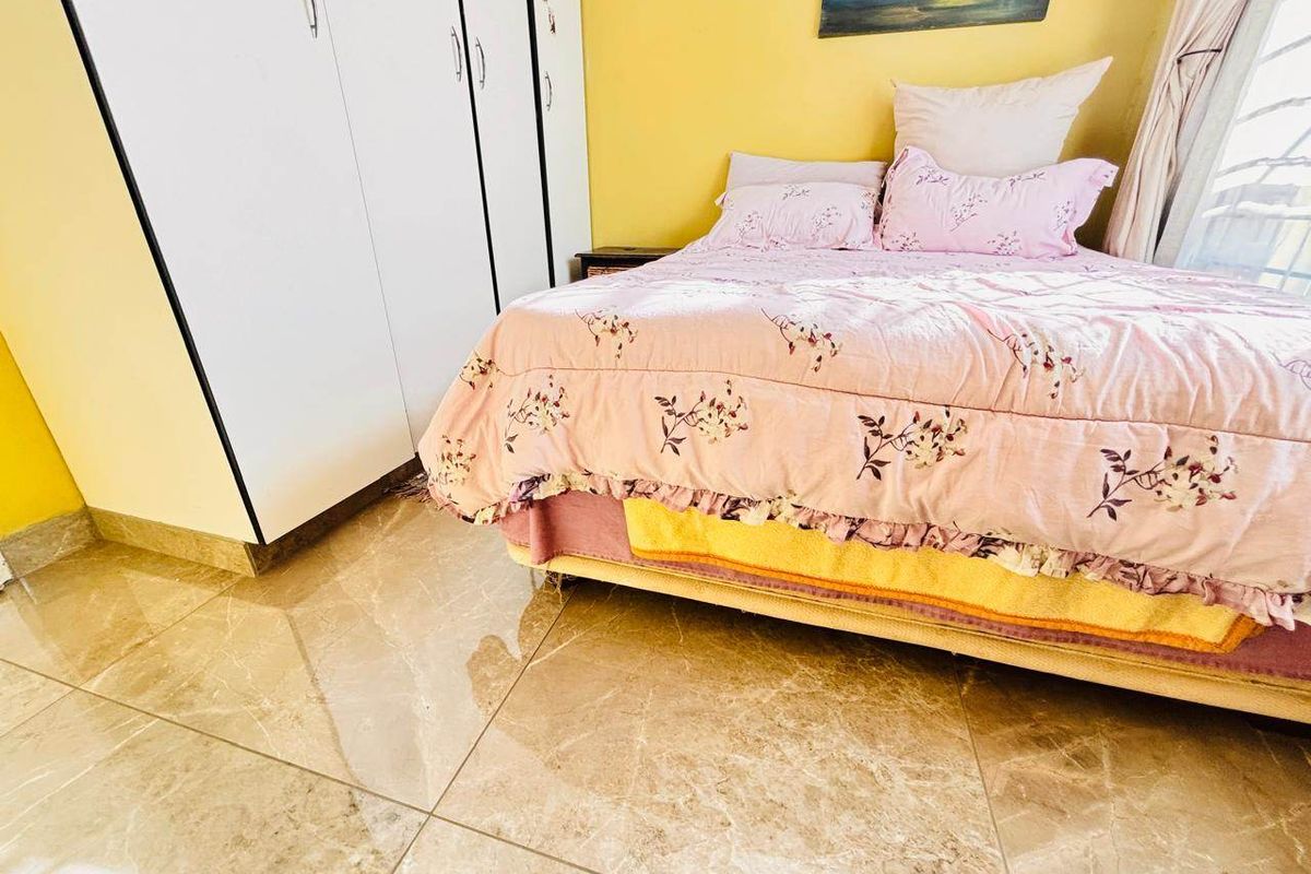 A bedroom featuring tiled flooring and a built-in wardrobe with white doors.