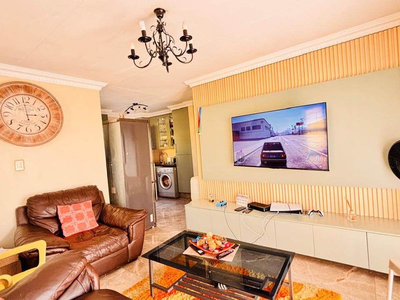 Open plan living area featuring tiled flooring, decorative coving, and a modern slatted feature wall with integrated media storage.